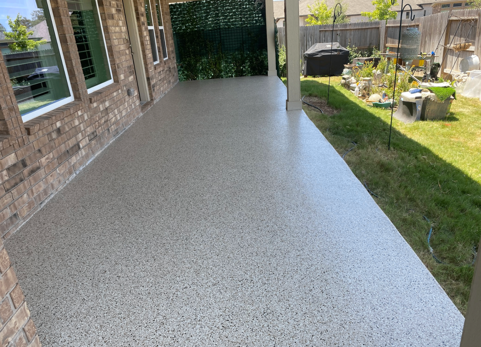 Neutral tan flake epoxy covered patio with brick home